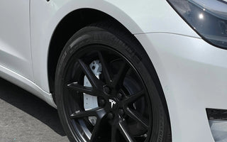 Front view of a white Tesla car showcasing its sleek wheel design and modern aesthetics